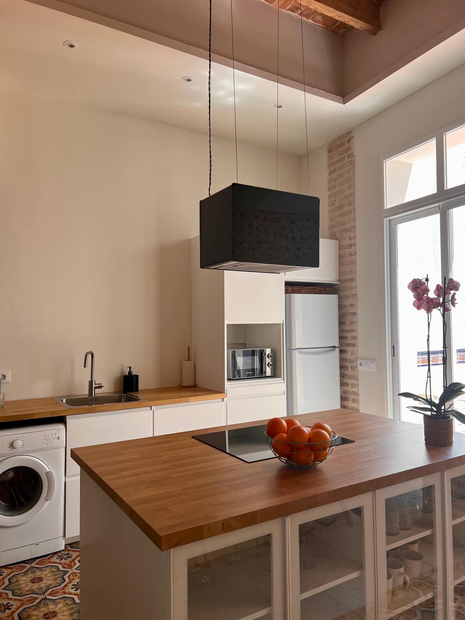 Cocina moderna con isla de madera, campana negra y suelo hidráulico - Casa Filo Xeresa