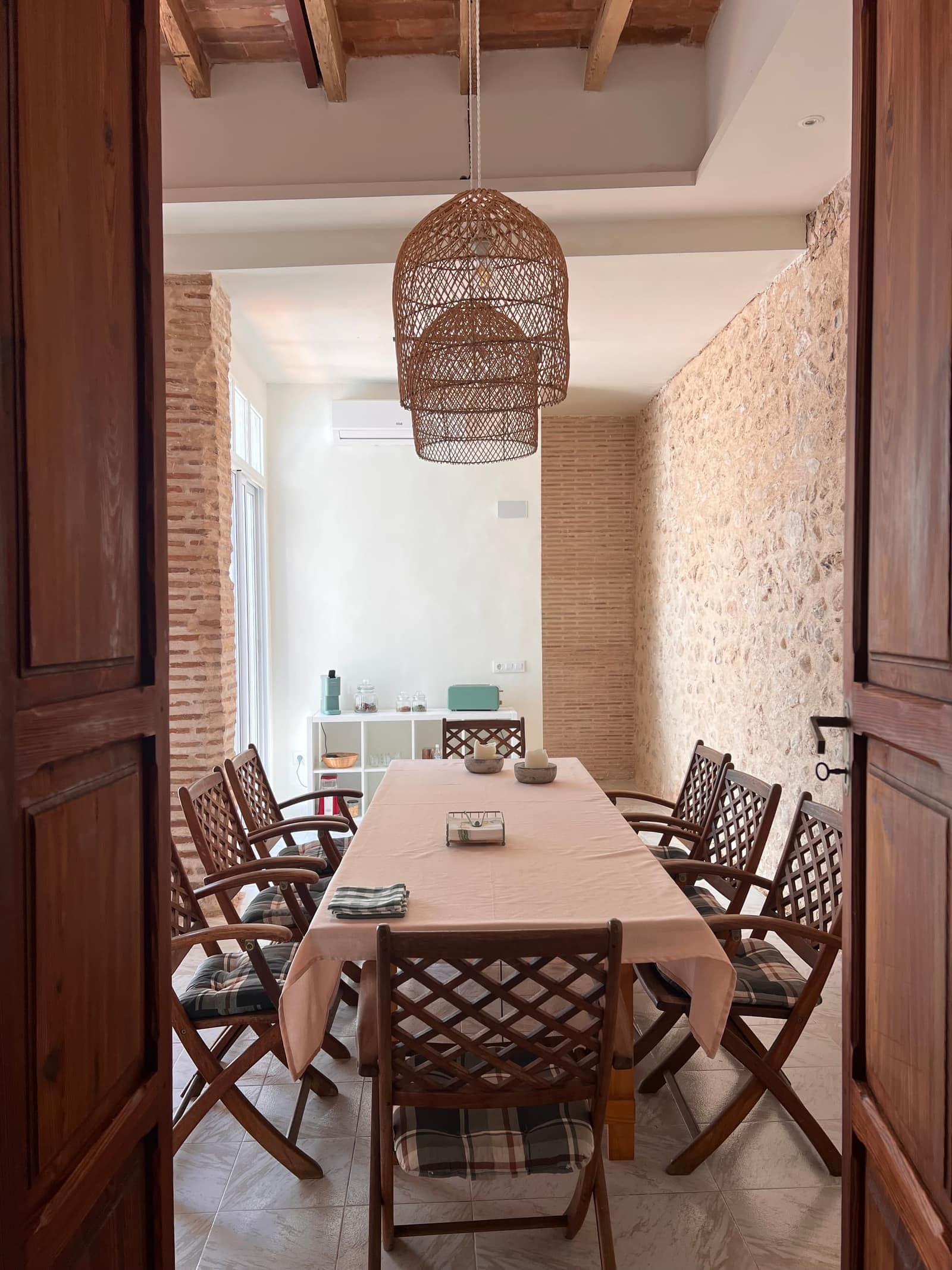 Comedor con lámpara de mimbre, mesa y sillas de madera - Casa centenaria Xeresa