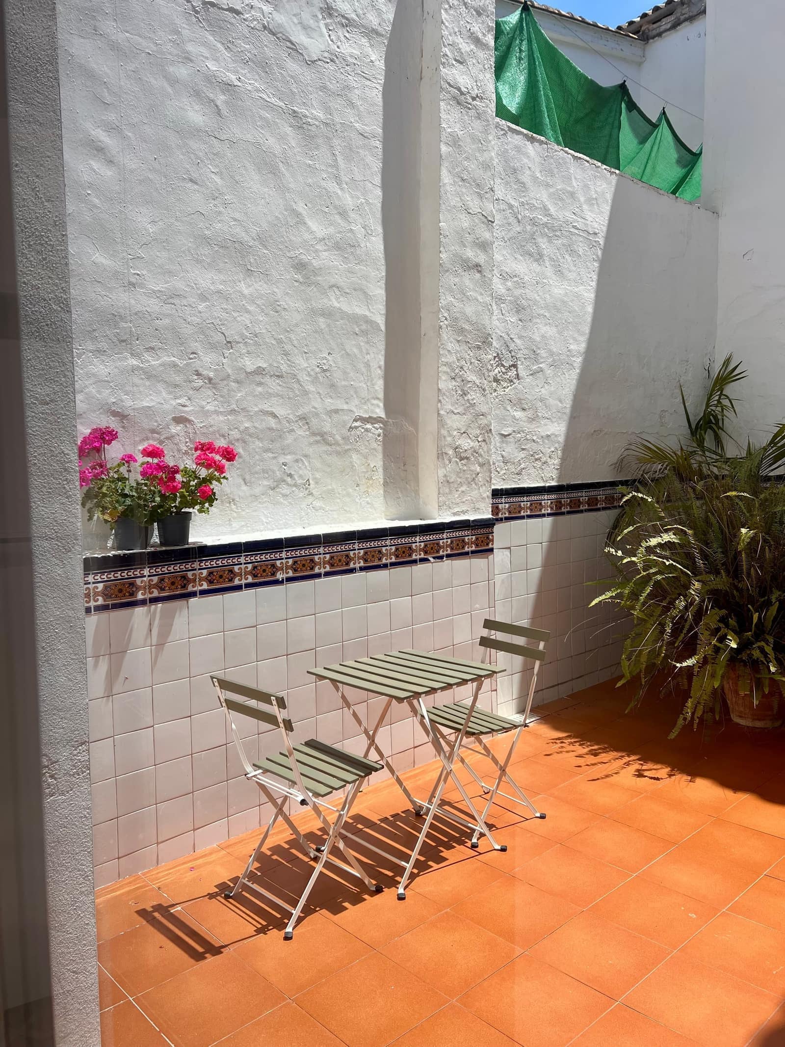 Patio interior con mesa y sillas, plantas y azulejos tradicionales - Casa Filo Xeresa